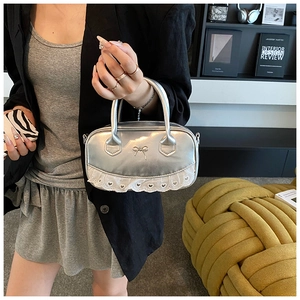 Detail of silver Boston bag with metallic bow and white lace hem with heart cutouts
