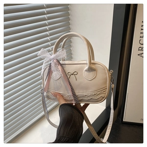 Detail of white PU bowling bag with metal bow buckle, lace trim, and pink ribbon accents