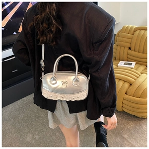Detail of silver metallic Boston bag with bow accent and white lace heart trim