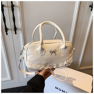 Close-up of white PU leather Boston bag with metal bow detail and heart lace trim