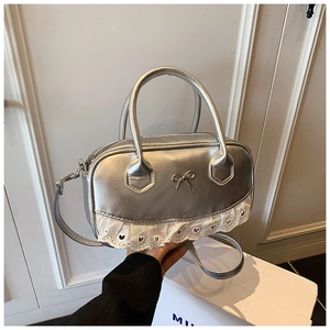 Detailed macro of silver metallic Boston bag with bow ornament and white lace trim