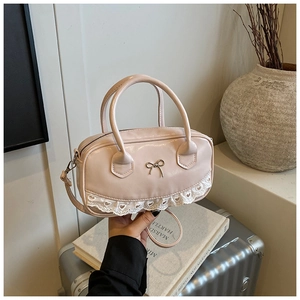 Pink Boston bag detail featuring delicate white lace trim and a metal bow accent