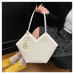 Detail of a chic tote bag with V-shaped cut, M-letter print, and golden metal charm