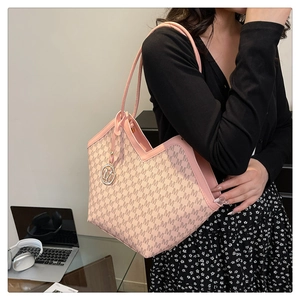 Detail of pink leather trim and M-pattern tote bag with a gold metal logo pendant
