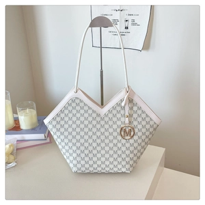 Detail of monogram patterned shoulder bag with gold M-shaped charm and V-shaped edge