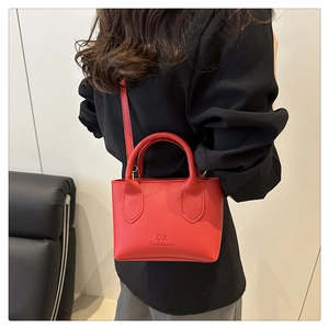 Red lychee grain crossbody bag with dual handles and slender strap on model back view