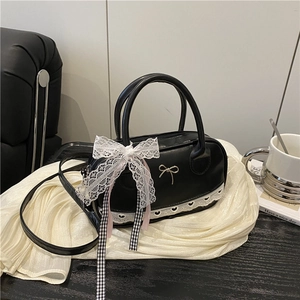 Black PU leather bowling bag with white lace trim and metallic bow detail on white cloth