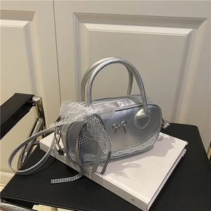Silver metallic bowling bag with lace bow and butterfly charm on a white book
