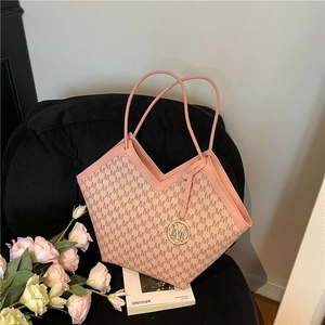 Pink monogram tote bag with V-shaped cut and M logo charm on a modern velvet chair