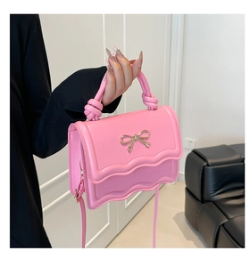 Détail du sac vintage rose avec nœud doré et bords festonnés élégants