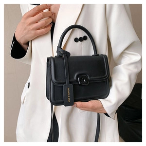 Detailed view of women's black square bag with matte leather finish and metal twist lock