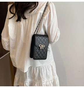 Dettaglio mini borsa trapuntata nera con chiusura a fiocco argento e catena