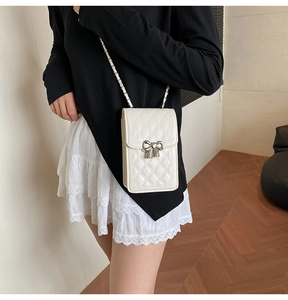 Dettaglio borsa a tracolla beige trapuntata con fiocco in metallo e tracolla a catena
