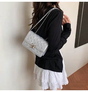 Détail du mini sac matelassé argenté avec boucle nœud métallique et bandoulière