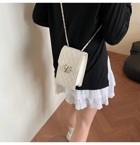 Vista dettagliata della borsa trapuntata bianca con fiocco argento indossata dal modello