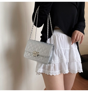 Sac argenté matelassé avec nœud en métal porté par un mannequin pour le style