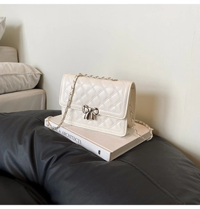 Détail du sac matelassé crème avec fermoir nœud argenté et bandoulière en chaîne