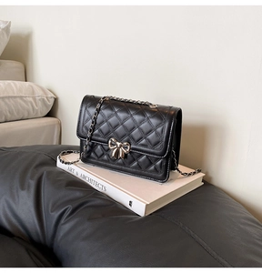Détail du sac bandoulière matelassé noir avec boucle nœud en métal argenté et chaîne