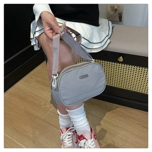 Detail of light purple nylon crossbody bag with wide strap and metallic logo plate