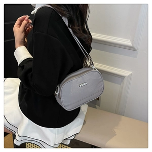Detail view of a grey nylon crossbody bag with JING PIN logo and smooth metal zipper