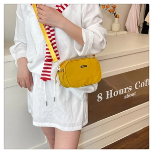 Yellow nylon crossbody bag with double zippers and adjustable strap shown on model