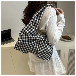 Détail du sac à bandoulière chic avec nœud en vichy noir et blanc sur un bureau blanc