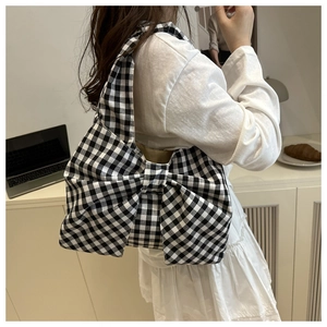 Vue détaillée du sac à bandoulière à nœud à carreaux noir et blanc dans un décor moderne