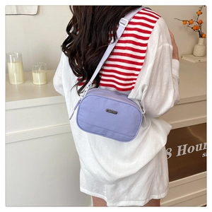 Detail of lavender nylon crossbody bag with adjustable strap and metal logo plate