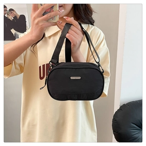 Detail of a black nylon crossbody bag with silver JINGPIN metal logo and adjustable strap