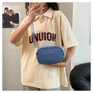 Blue nylon crossbody bag shown on model featuring an adjustable grey fabric strap
