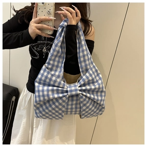 Selfie miroir montrant un sac fourre-tout à carreaux bleus et blancs avec un grand nœud