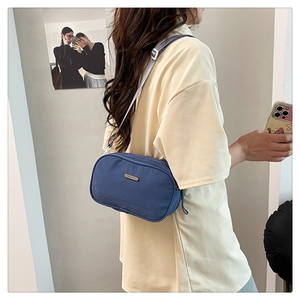 Detailed shot of a blue nylon crossbody bag with adjustable strap and metal brand tag