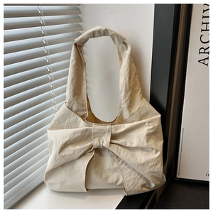Gros plan du sac à main crème à nœud avec texture plissée sous la lumière naturelle