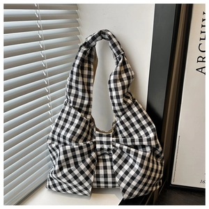 Détail du sac à main à carreaux vichy avec un grand nœud sur un rebord de fenêtre