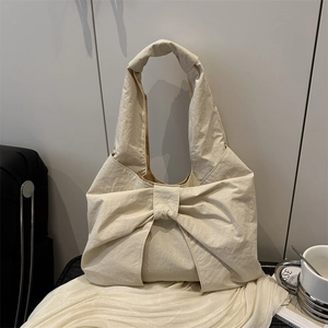 Sac bandoulière beige avec grand nœud décoratif en tissu souple au style épuré