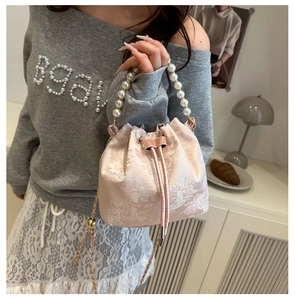 Detail of pink satin bucket bag with pearl handle, landscape embroidery and gold chain strap