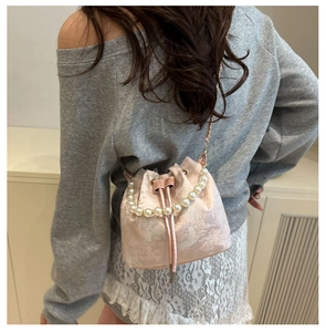 Detail of pink jacquard bucket bag featuring elegant pearl handle and drawstring design