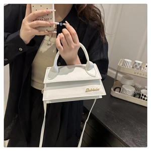 Vue détaillée d'un mini sac en cuir blanc avec logo doré et longue bandoulière