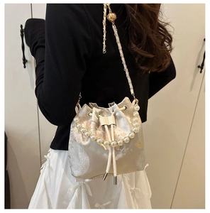 Detail of floral bucket bag with pearl handle and leather chain strap shown on model