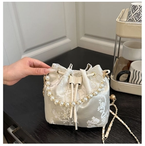 Close-up of intricate floral embroidery on the satin bucket bag with pearl handle