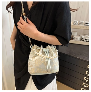 Close-up of pearl handle and golden embroidery on the light blue drawstring bucket bag