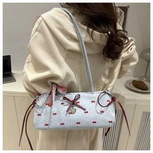 Close-up of light blue canvas shoulder bag with red bows and lace tassels for women