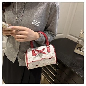 Detail of red bow, polka dot fabric, and heart-shaped metal charm on small handbag