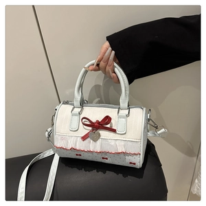 Detail of Boston bag showing red bow, heart pendant, and delicate floral lace textures