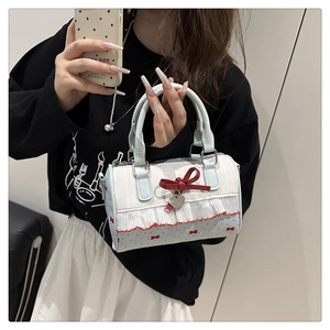Detail of sweet cylindrical handbag with red bow patterns and frill trim accents