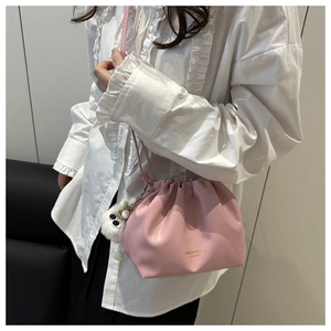 Detail shot of a pink pleated drawstring bucket bag with a white fuzzy keychain ball