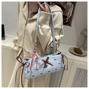 Close-up of light blue polka dot shoulder bag with bows on a cozy desk setting