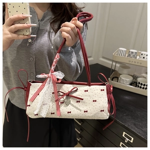 Detailed shot of cream shoulder bag featuring red polka dots and chic bow accessories