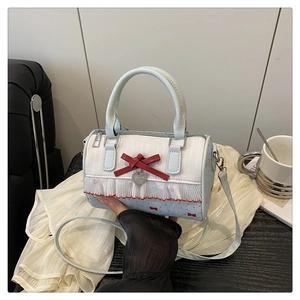 Close-up of blue cylinder bag with red bow, heart pendant and delicate lace details