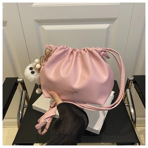 Detail of pink pleated cloud bucket bag with gold lettering and cute plush charm on white book